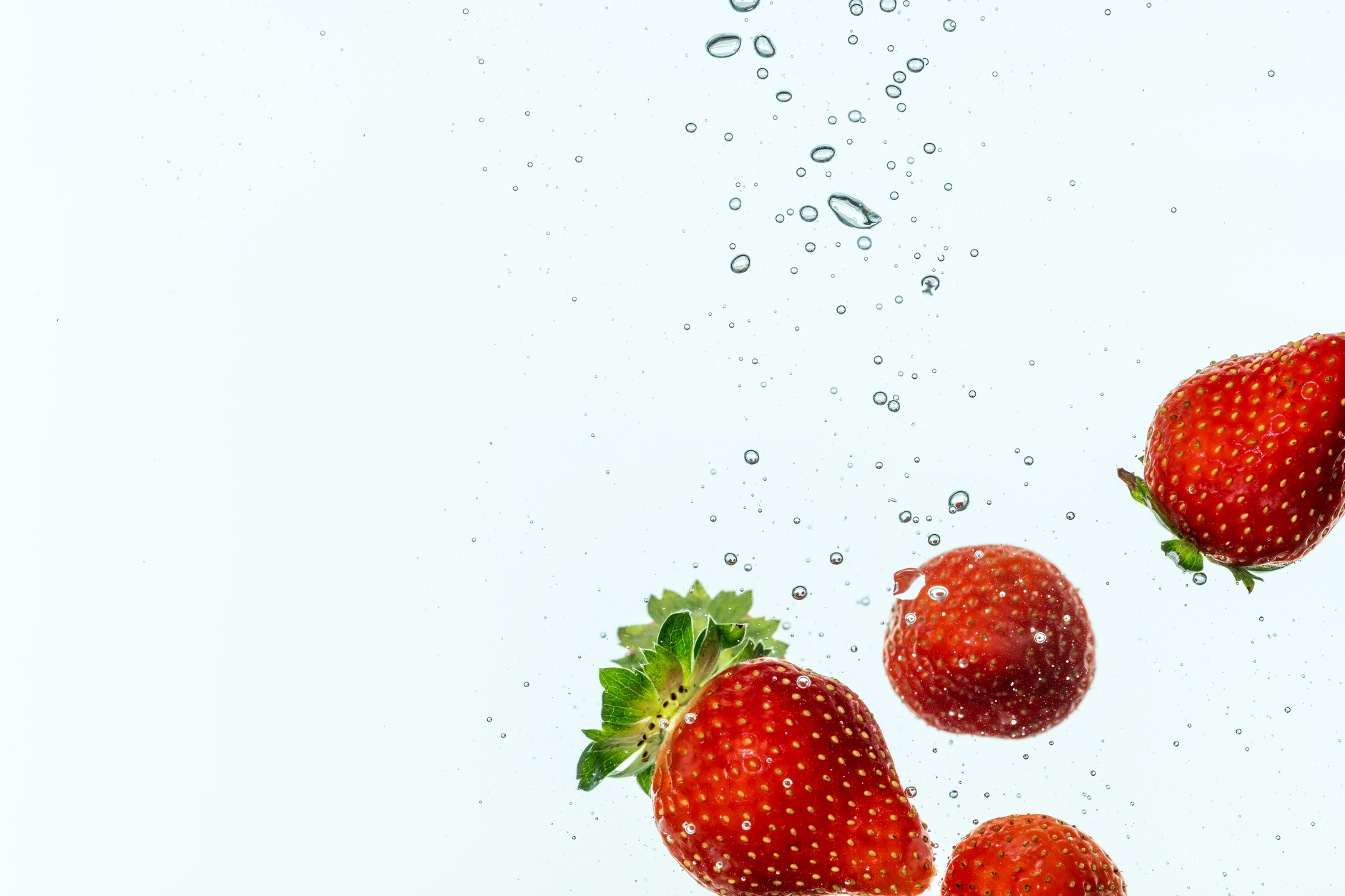 Fresas vibrantes sumergidas en agua, mostrando frescura y movimiento.