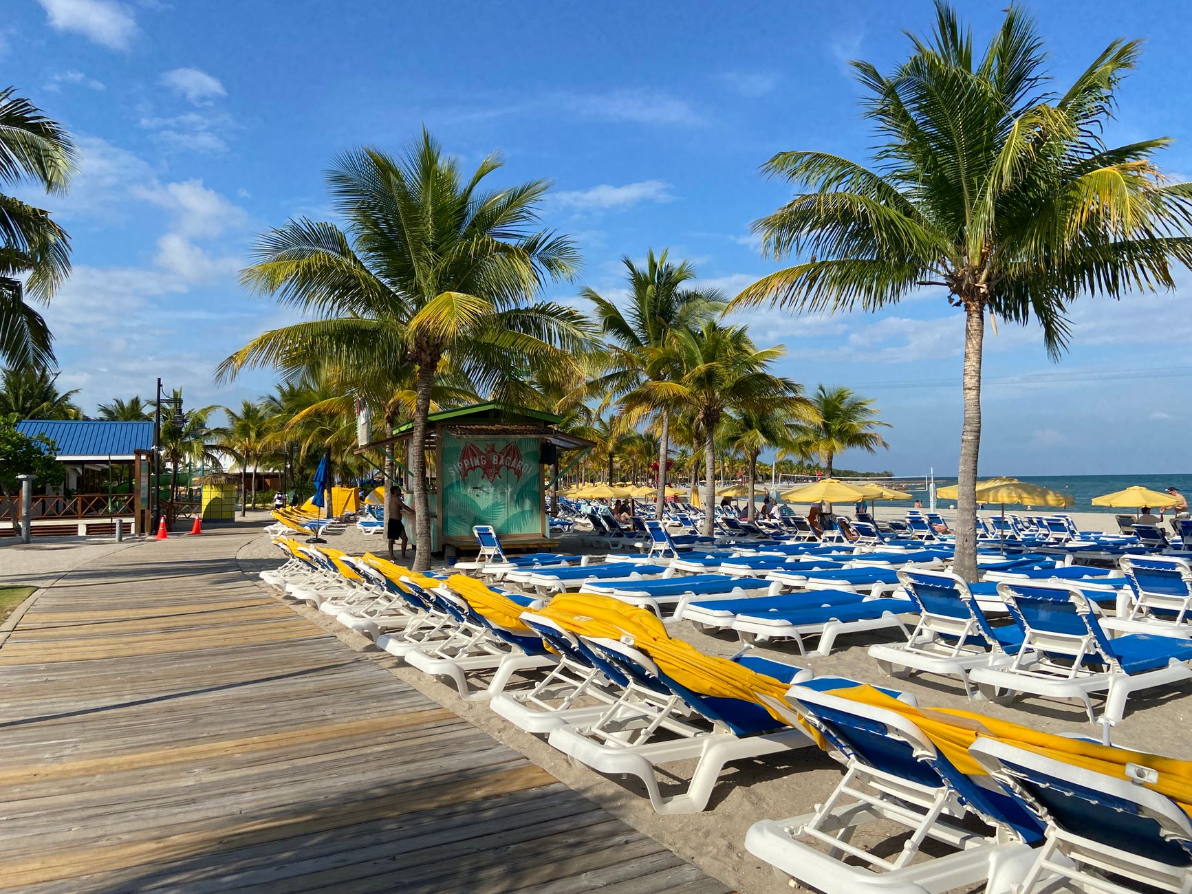 Serena escena de playa tropical con palmeras, tumbonas y un cielo azul claro en Belice.